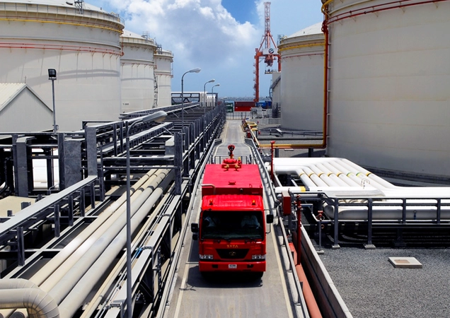truck amongst pipelines and storage tanks